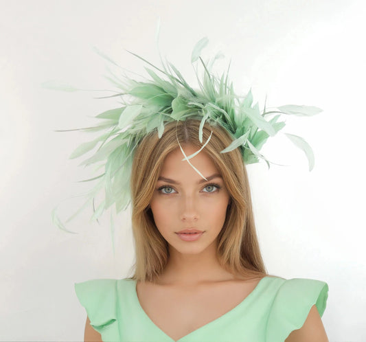 Woman wearing a pale green Pasha Feather Halo Crown Fascinator Hat with soft feathers and an elegant formal design